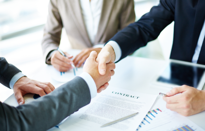 A group of business people shaking hands at a table.