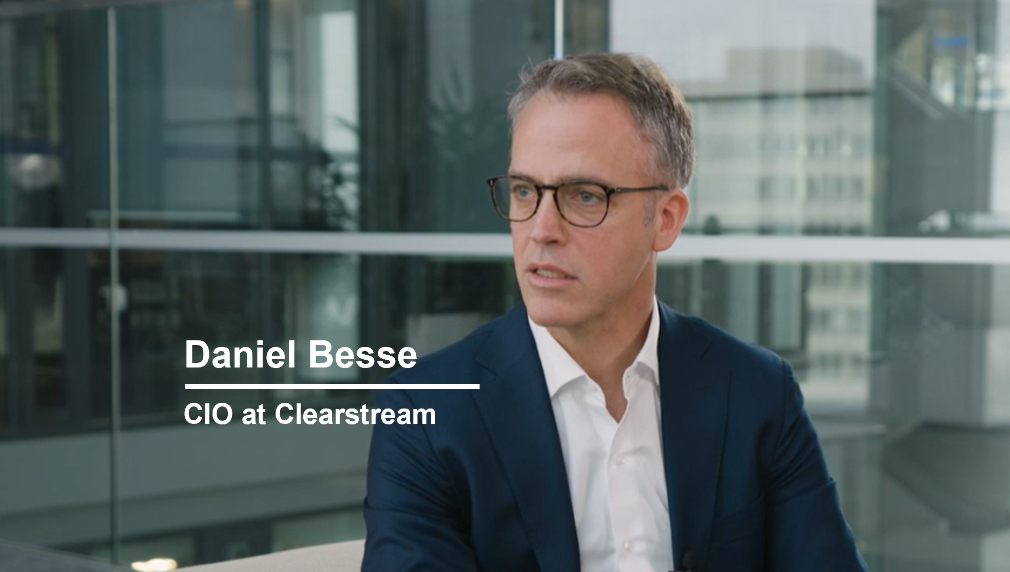 Middle-aged man in glasses and a navy suit sitting in an office setting, with the name "daniel besse" and title "cio at clearstream" displayed.